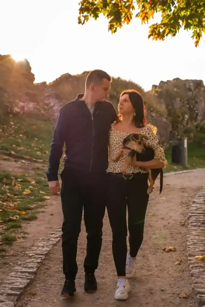 Sesja rodzinna – para spacerująca z psem o zachodzie słońca